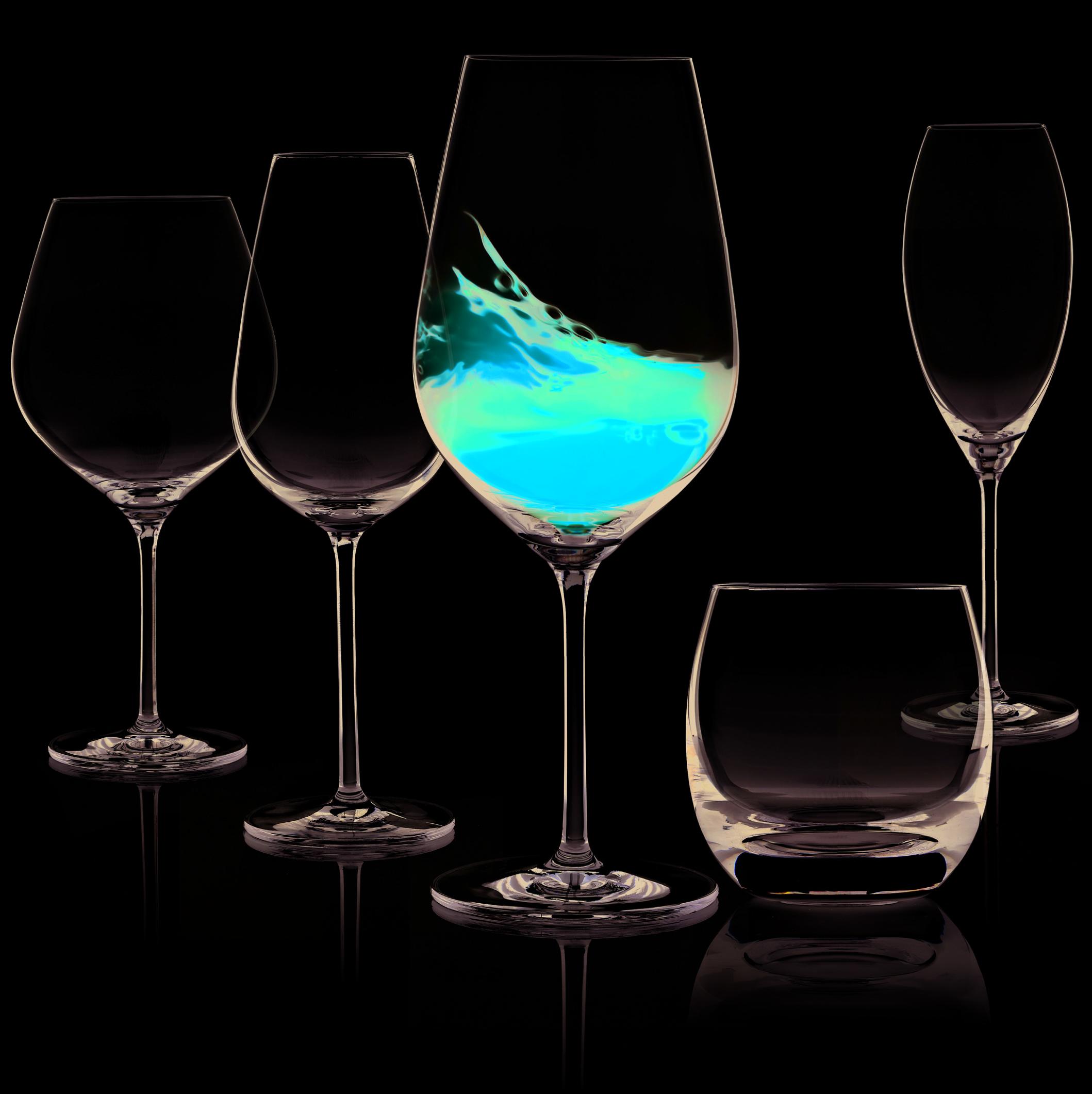 Taiteellinen kuva, jossa viisi erilaista viinilasia mustalla taustalla. Yhdessä lasissa sisällä nestettä, joka läikähtää.