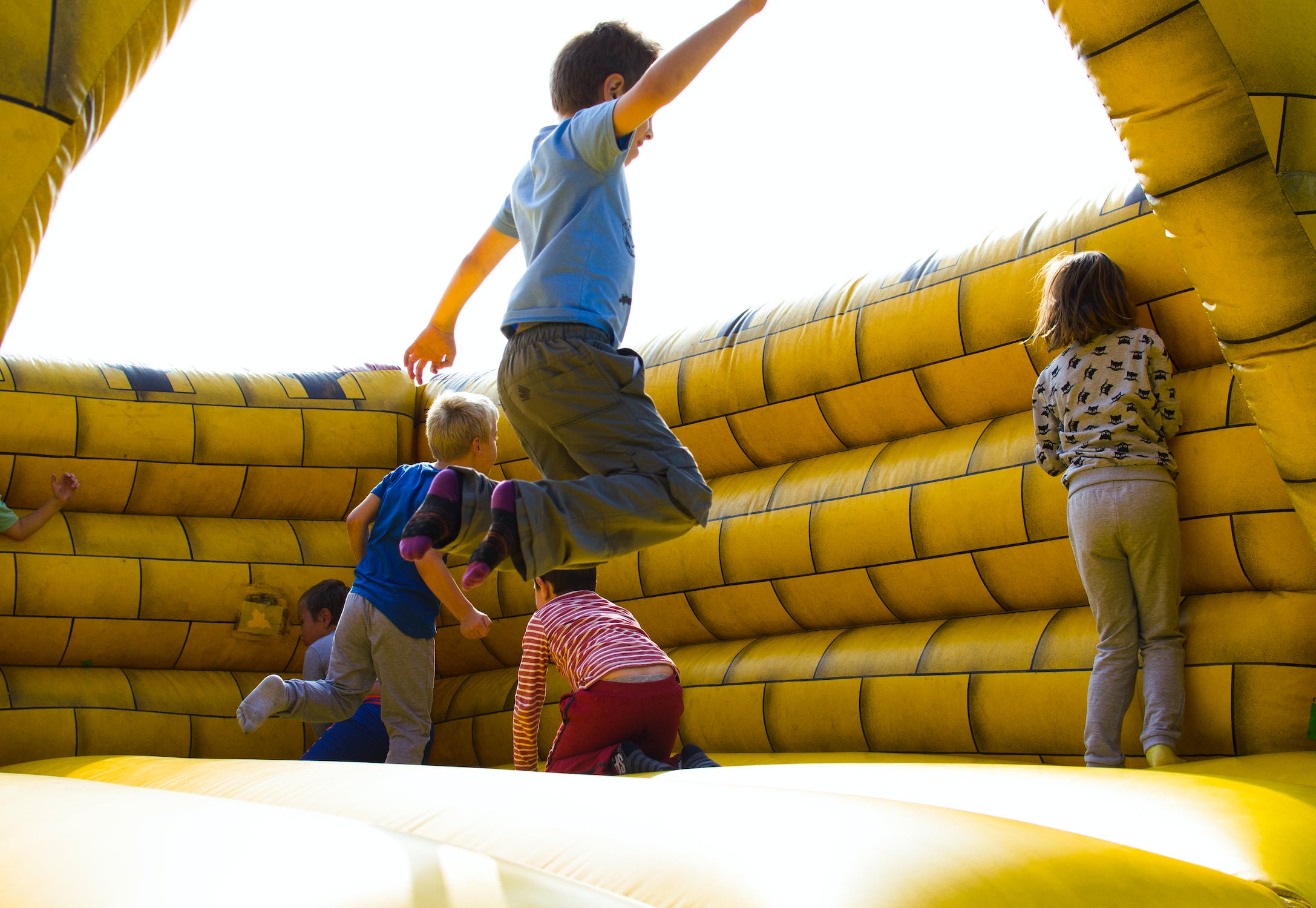 Lapset hyppivät ja leikkivät keltaisessa pomppulinnassa