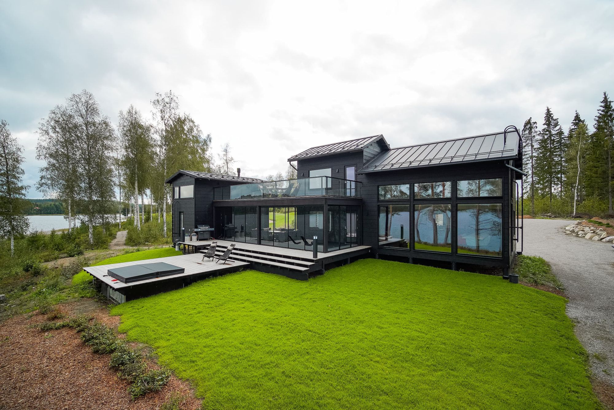 Modernin tyylikäs huvila Villa Griini isoilla ikkunoilla, iso terassi ja nurmialue järven rannalla - Venuu.fi