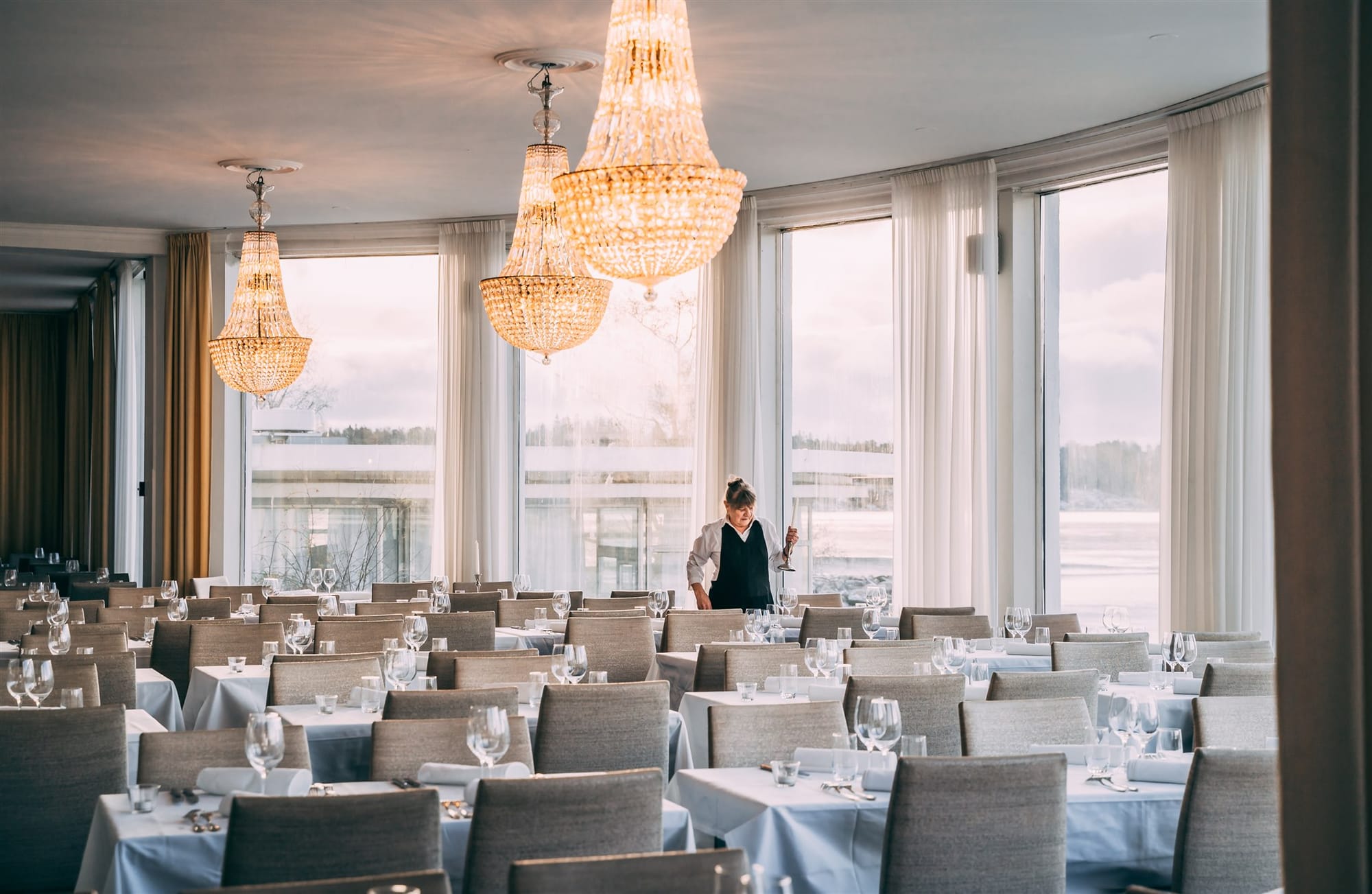 Kulosaaren Casinon Merisalin pöydät katettuna, tilaa koristaa upeat kristallikruunut ja näkymät merelle - Venuu.fi