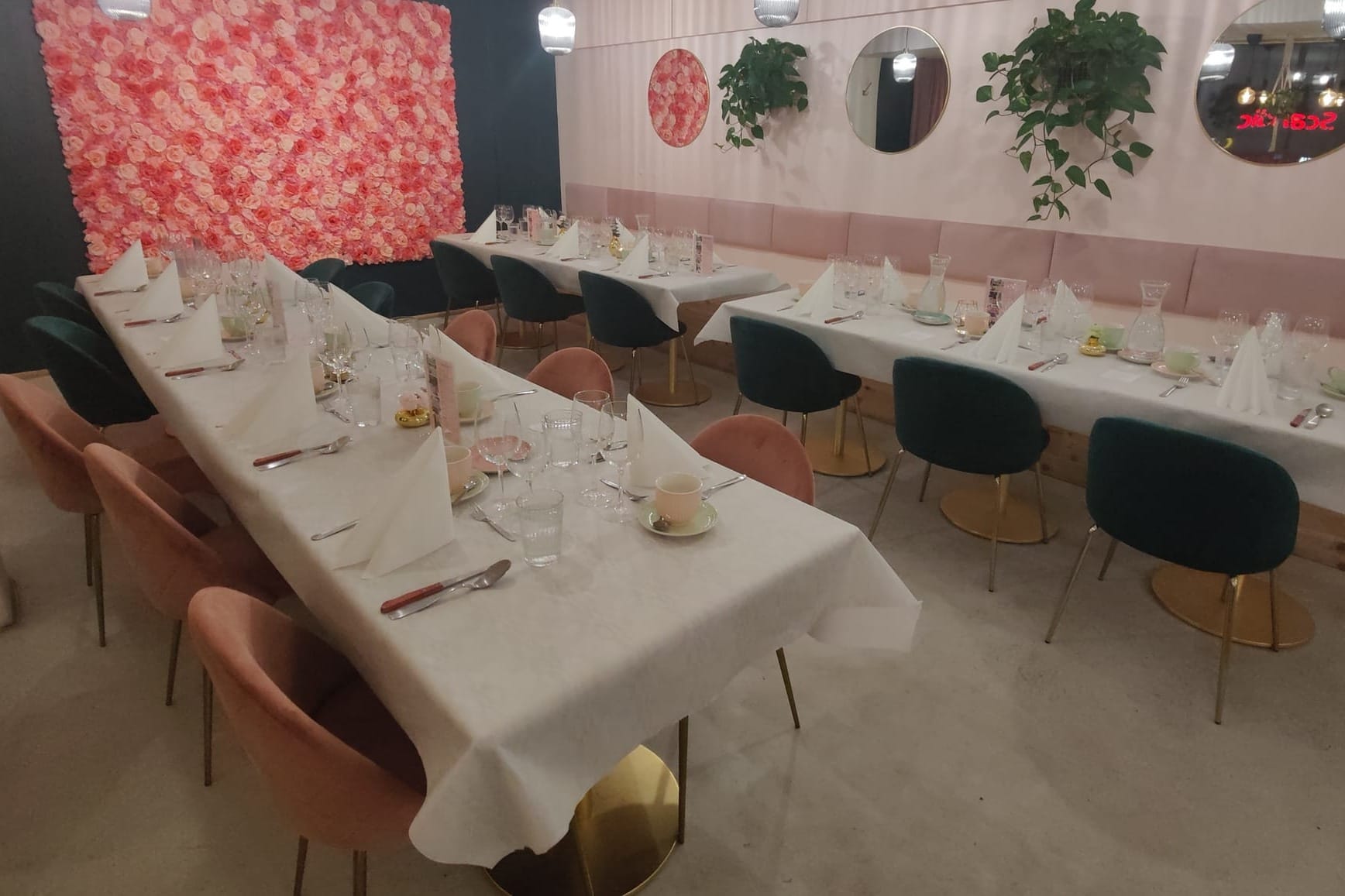 Rebelle Bakeryn vaaleanpunaisin ja tummanvihrein yksityiskohdin sisustetun ravintolasalin pöydät katettuna juhlaan - Venuu.fi