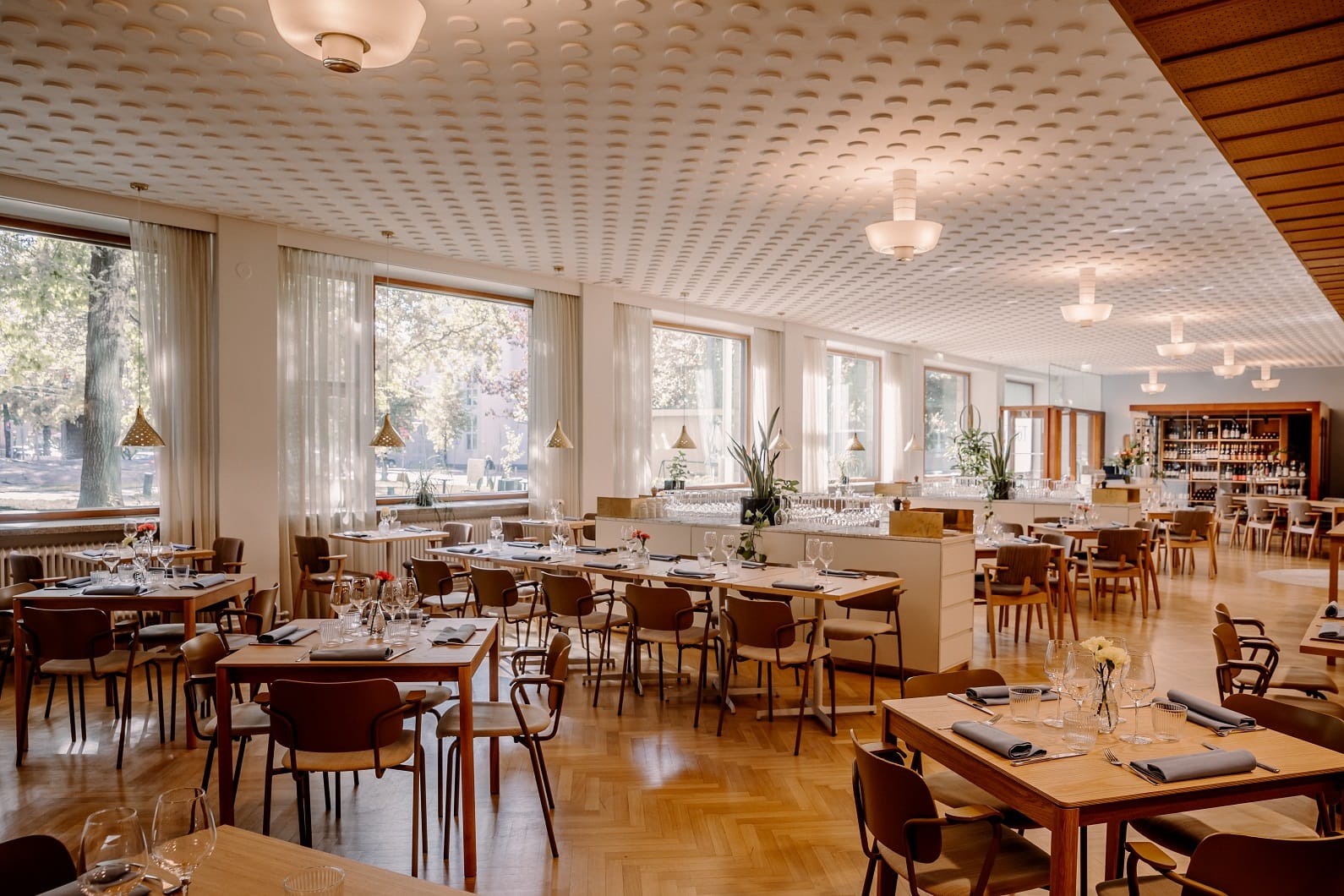 Tyylikäs Ravintola Töökön ravintolasali katettuna, taustalla isot ikkunat - Venuu.fi