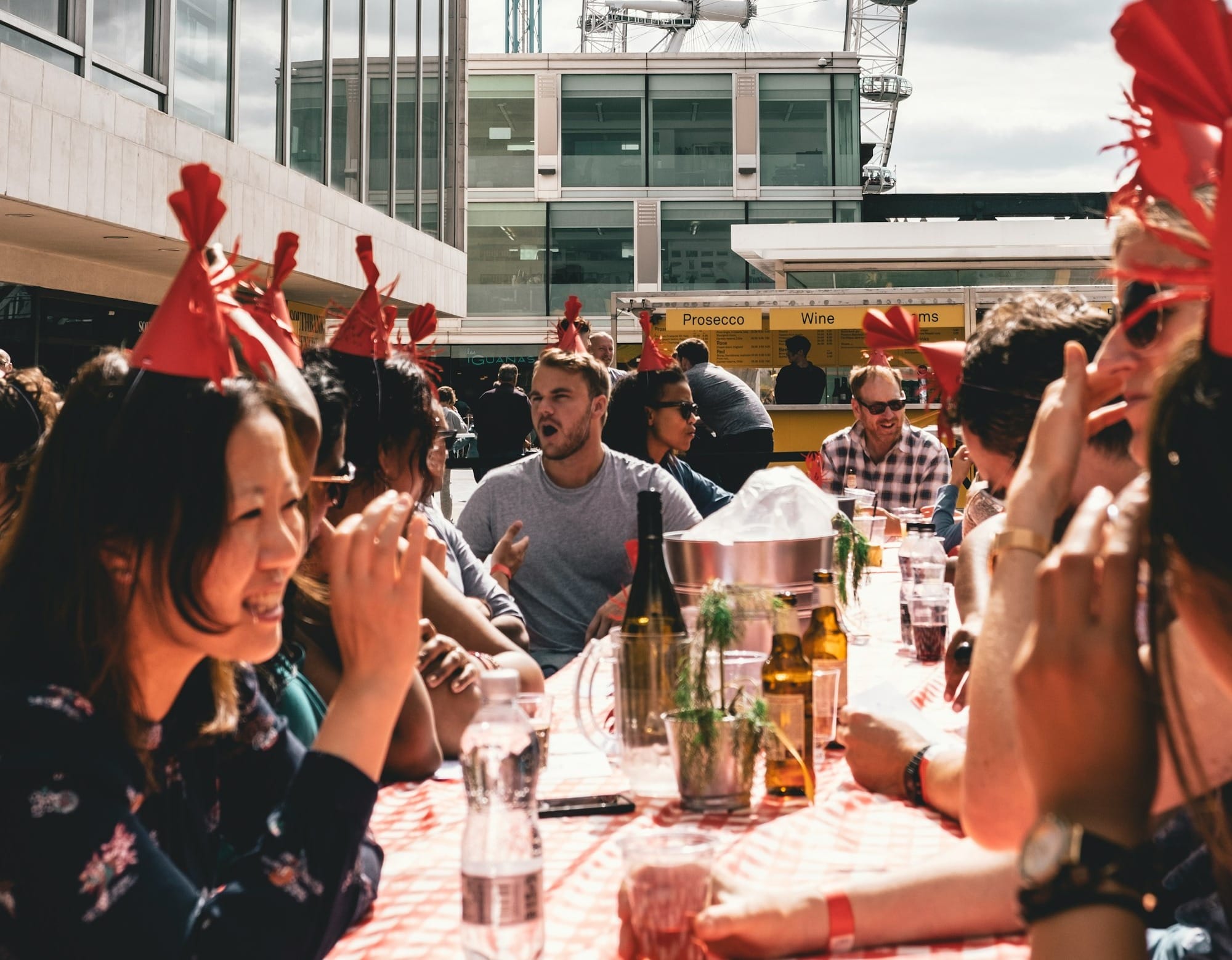 people dining outside building near ferris wheel